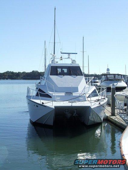 White catamaran yacht docked at a pier, front view, clear sky