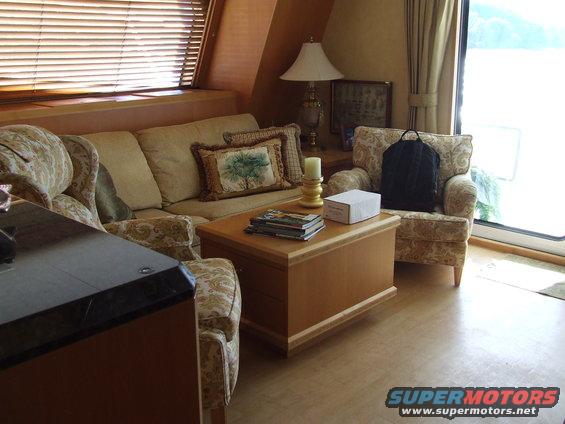 Interior living space with sofa, armchair, coffee table, and blinds covering a window