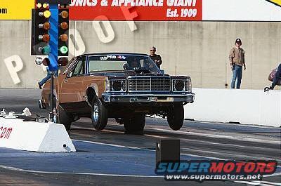 Drag racing car with hood scoop on track, front wheels off ground