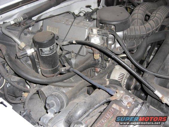 engine bay with hoses, battery, and alternator visible