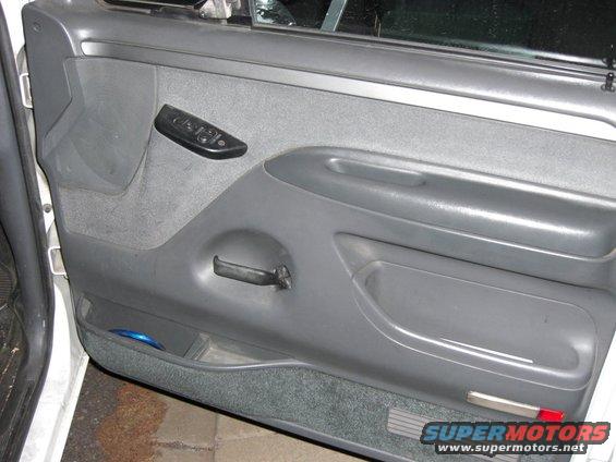 Gray interior door panel with power window controls and manual door handle
