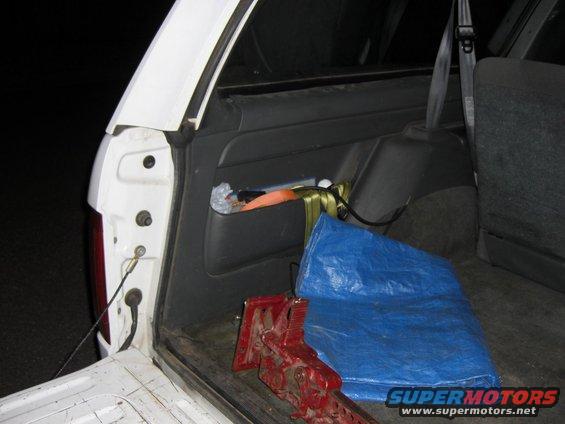 Interior cargo area with red jack and blue tarp. Visible storage compartment with items