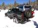 1979 Ford Bronco - Two modified off-road vehicles are stuck in the snow, with a forest in the background.