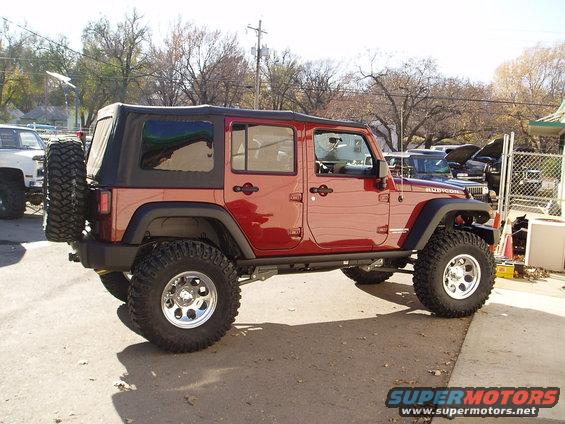 Red Jeep Wrangler Rubicon lifted with large tires, side view
