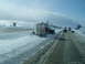 1995 Mercury Grand Marquis - A semi-truck is stuck in a snowdrift on the side of a highway, with other vehicles driving past.