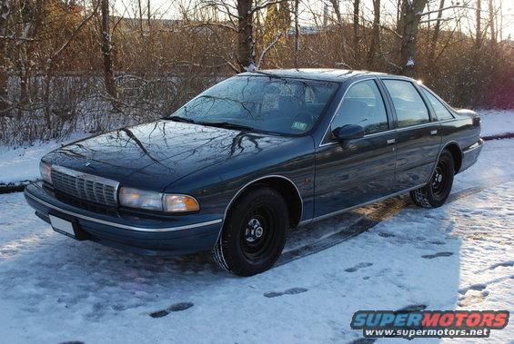 Dark blue 1996 Chevrolet Caprice sedan parked on a snowy surface, trees in background