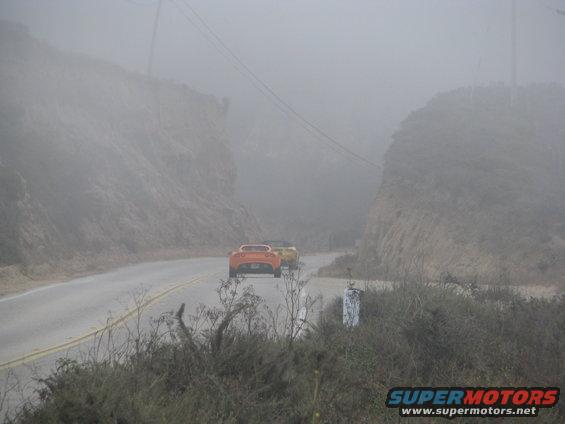 Orange and yellow sports cars on a foggy road
