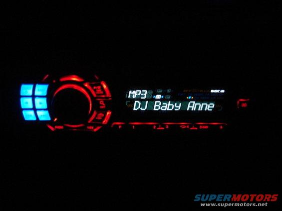 Car stereo displaying "DJ Baby Anne" with blue and red lights