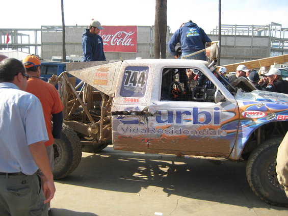 off-road race truck with number 744, covered in mud, with sponsors like Urbi Vida Residencial