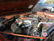 1972 Ford Bronco - Engine bay of an orange vehicle with chrome accents and an aftermarket air filter, with another vehicle in the background.