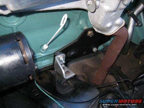 Close-up of engine bay showing a dipstick, exhaust pipe, and mounting bracket