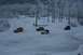 1990 Chevrolet Suburban - Several SUVs navigate a snowy landscape, surrounded by frosted trees under a dim sky.