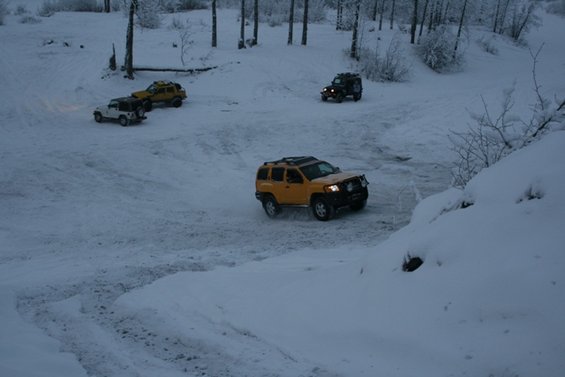 Yellow SUV with roof rack and brush guard driving on a snow-covered road