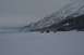 1990 Chevrolet Suburban - Several vehicles traverse a wide, snow-covered area with a mountain range looming in the distance.
