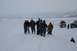 1990 Chevrolet Suburban - A group of people stand in a snowy landscape with vehicles parked in the background.