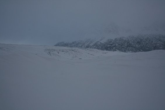 Snowy landscape with mountains under a cloudy sky