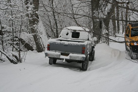 Gray pickup truck's rear in snow, yellow SUV visible to the right