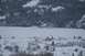 1990 Chevrolet Suburban - Two SUVs traverse a frozen, snow-covered lake surrounded by wintery forests and mountains.