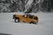 1990 Chevrolet Suburban - SUV stuck in snowdrift with snowy mountains and trees in background.
