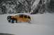 1990 Chevrolet Suburban - A yellow SUV navigates a snow-covered landscape, with , snow-dusted mountains rising behind it.