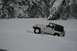 1990 Chevrolet Suburban - A Jeep navigates a snowy landscape with steep, tree-covered cliffs in the background.