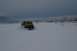 1990 Chevrolet Suburban - A yellow SUV navigates a snowy landscape under a cloudy sky.