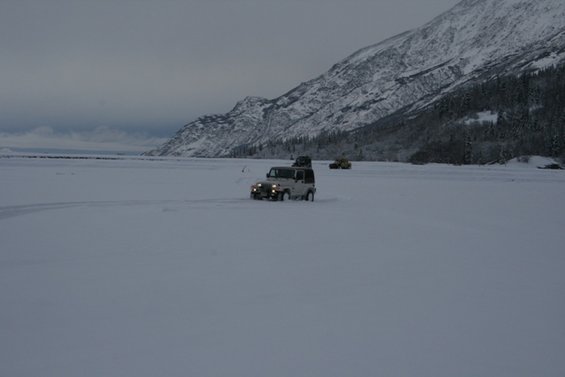 White Jeep Wrangler driving through snow with other vehicles in background