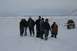 1990 Chevrolet Suburban - A group of people stand in a snowy landscape next to a yellow SUV that appears to be stuck in the snow.