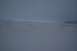 1990 Chevrolet Suburban - A wide, snow-covered landscape stretches out under an overcast sky, with distant mountains barely visible.