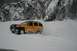 1990 Chevrolet Suburban - A yellow SUV navigates a snowy landscape with steep, tree-covered mountains in the background.