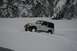 1990 Chevrolet Suburban - A Jeep navigates a snowy landscape, kicking up snow as it goes.