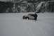 1990 Chevrolet Suburban - A white Jeep Wrangler is stuck in deep snow with a person standing next to it, surrounded by a winter landscape.