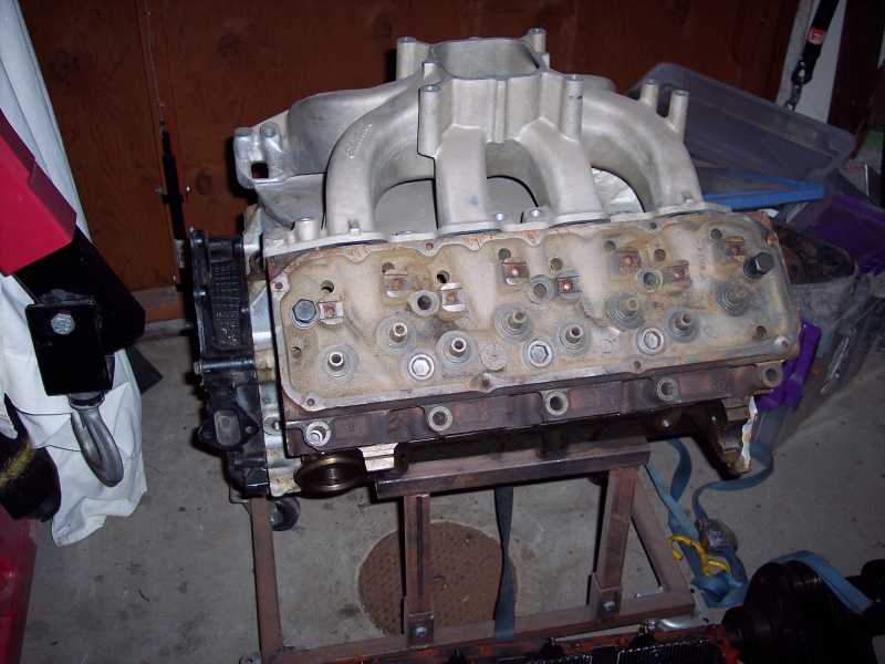Engine block with intake manifold on a stand, showing cylinder heads and valve train components