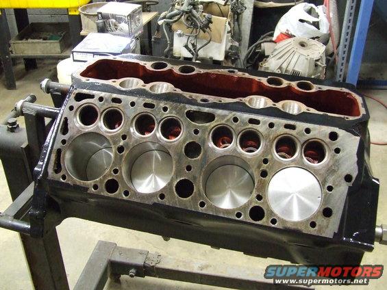 Engine block on stand, showing cylinders and internal components. Black and red paint