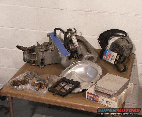 Carburetor, fuel injectors, alternator, and ECU on a table