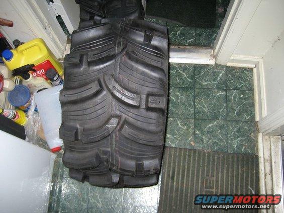 ATV tire with aggressive tread pattern, lying flat indoors