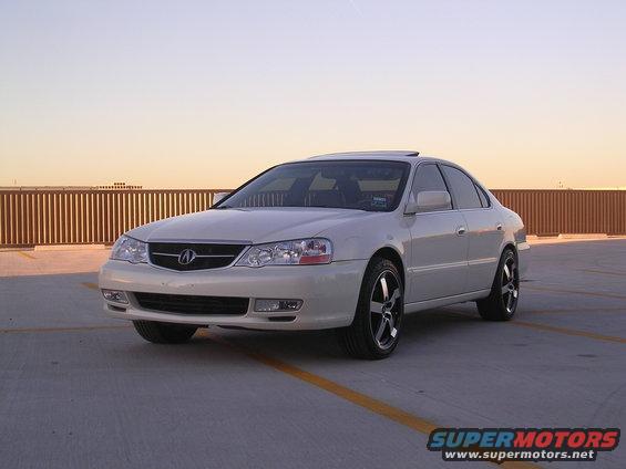 White 2003 Acura TL parked on a concrete surface with a wooden fence in the background