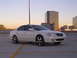 2003 Acura TL - A white 2003 Acura TL is parked on a rooftop with aftermarket wheels and city buildings in the background.