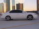 2003 Acura TL - A white 2003 Acura TL is parked in a lot with modern buildings reflecting the sunset.