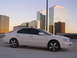 2003 Acura TL - A white 2003 Acura TL sedan is parked in a lot with skyscrapers in the background during sunset.