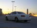 2003 Acura TL - A white 2003 Acura TL sedan is parked on a rooftop during sunset, with city buildings in the background.