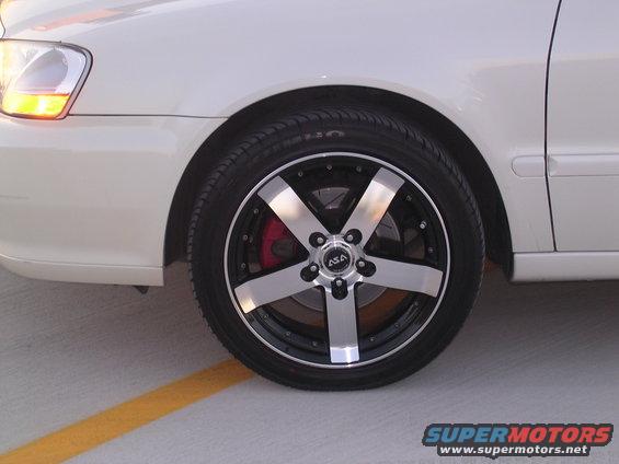 Close-up of a five-spoke aftermarket wheel with black and silver accents on a white car