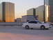 2003 Acura TL - A white 2003 Acura TL sits on a parking deck at sunset, with reflective glass buildings behind it.