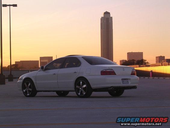 White sedan parked on a rooftop at sunset, showing its rear and side profile