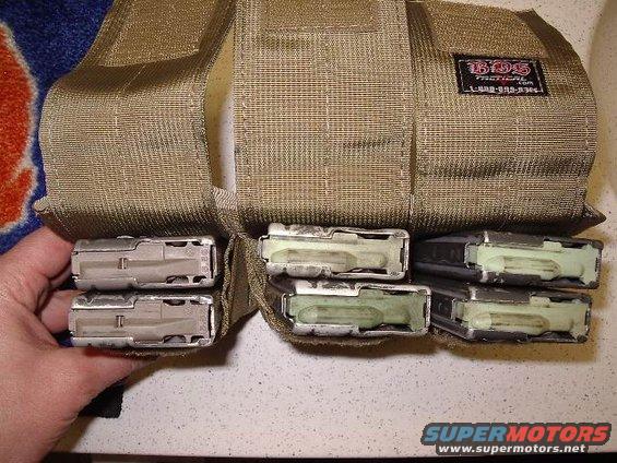 Tan tactical pouch holding six loaded magazines, with a hand inserting another