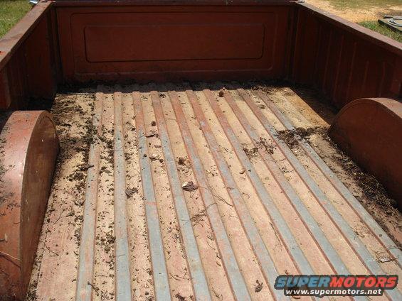 Interior of a dirty truck bed with wooden planks and metal strips