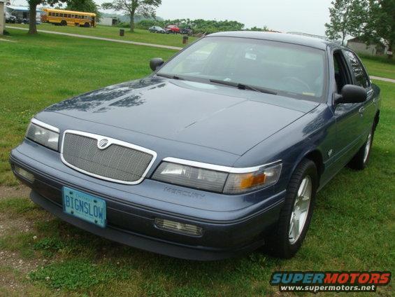 Blue Mercury Grand Marquis parked on grass. License plate reads BIGNSLOW. Text 'MERCURY' visible on the front fender