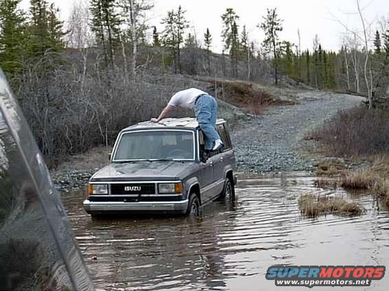 Isuzu Trooper stuck in water, guy on roof