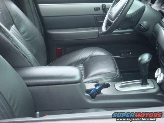 Car interior showing leather seats, center console with gear shifter, and steering wheel