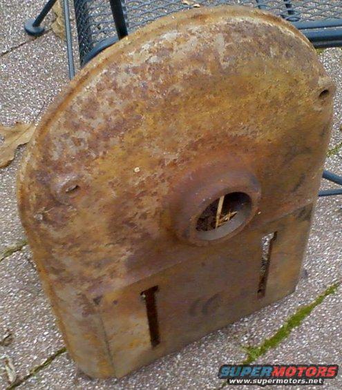 rusted metal part with a circular opening and two rectangular slots